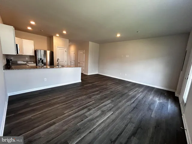 a view of kitchen and empty room with wooden floor