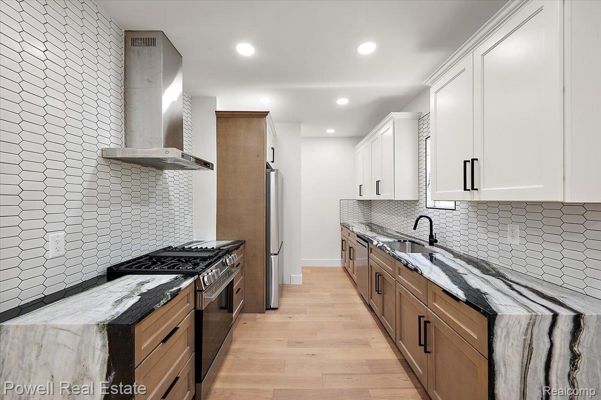 6837 Hatchery Road Waterford, MI 48327 - Photo 16 of 56 Dual tone kitchen featuring light stone countertops, stainless steel appliances, light wood-type flooring, two tone color scheme, and recessed lighting