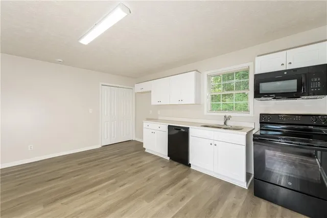 a kitchen with granite countertop a stove top oven a sink dishwasher and a microwave oven with wooden floor