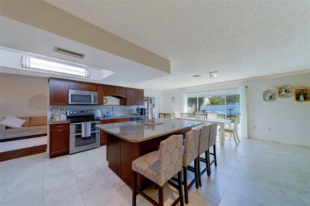 a large kitchen with stainless steel appliances kitchen island granite countertop a large counter top and a stove