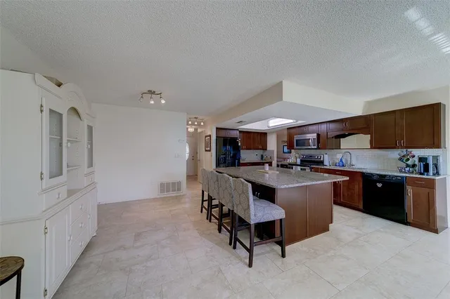a room with stainless steel appliances kitchen island granite countertop a sink and cabinets