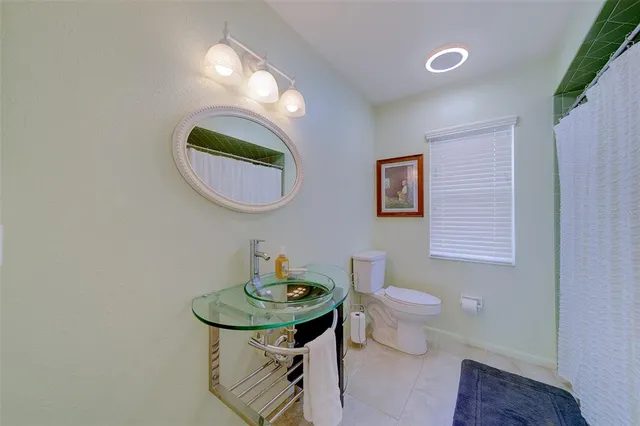 a bathroom with a granite countertop toilet a sink and a mirror