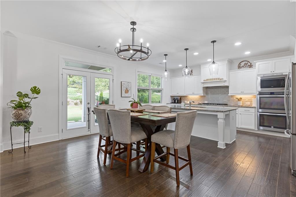 4867 Hunters Grove Way Sugar Hill, GA 30518 - Photo 17 of 61 a view of a dining room with furniture a kitchen and chandelier