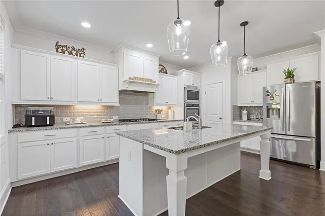 a kitchen with granite countertop white cabinets stainless steel appliances and a counter space