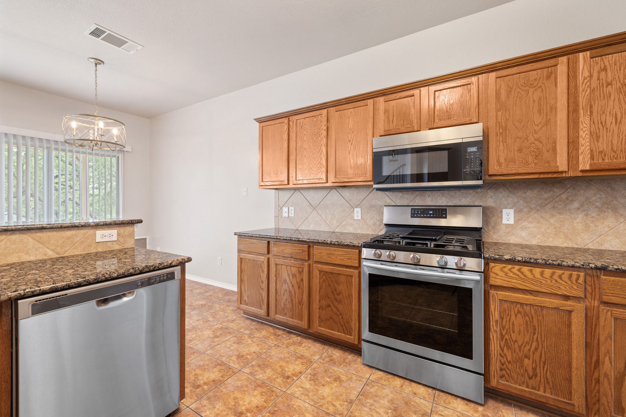 403 Red Hawk Drive Leander, TX 78641 - Photo 13 of 37 Kitchen featuring wood cabinetry, granite countertops, stainless steel appliances, and a tiled backsplash