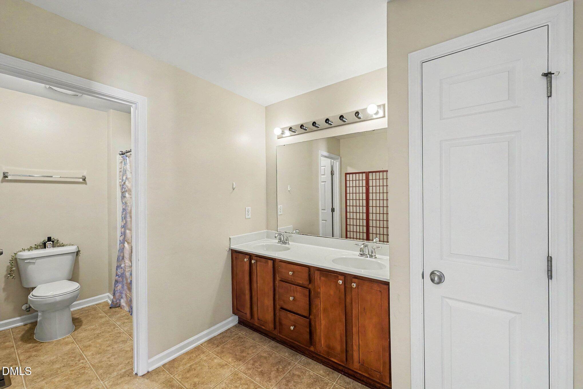 1130 Renewal Place, Unit 106 Raleigh, NC 27603 - Photo 16 of 34 a spacious bathroom with a granite countertop sink a toilet and a mirror
