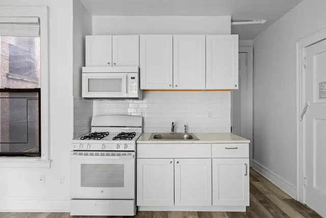 a kitchen with granite countertop a sink stove and cabinets