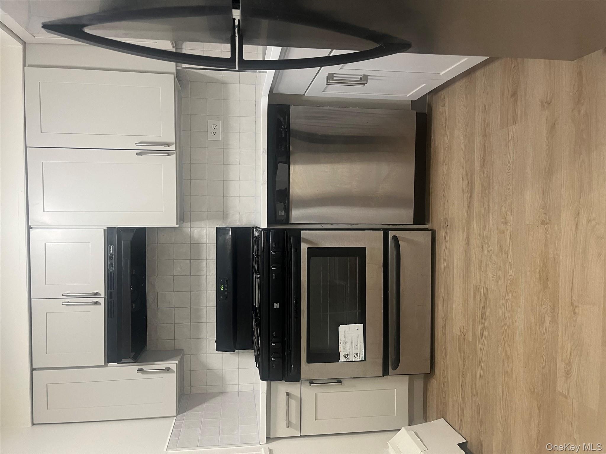 61-25 97th Street, Unit 1D Queens, NY 11374 - Photo 5 of 14 Kitchen with black range oven, stainless steel dishwasher, fridge, extractor fan, and light wood finished floors