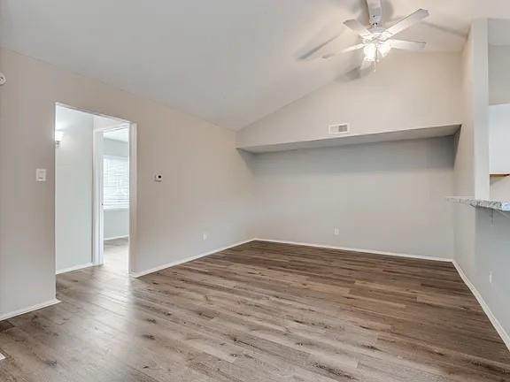 7125 Sorcey Road Dallas, TX 75249 - Photo 3 of 10 Unfurnished living room featuring lofted ceiling, dark wood-type flooring, and ceiling fan