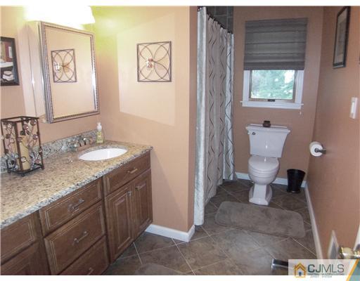 9 Glendale Road Colonia, NJ 07067 - Photo 8 of 19 a bathroom with a granite countertop sink a toilet and a mirror