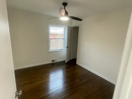 an empty room with wooden floor chandelier fan and windows
