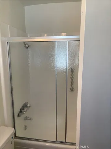 an empty room with wooden floor closet and windows