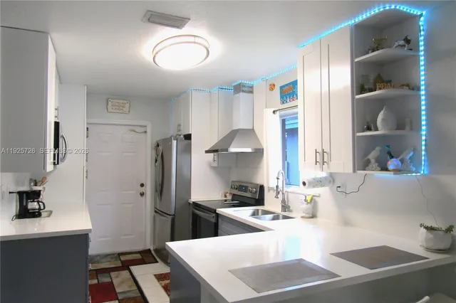 a kitchen with stainless steel appliances a refrigerator a sink a stove and white cabinets