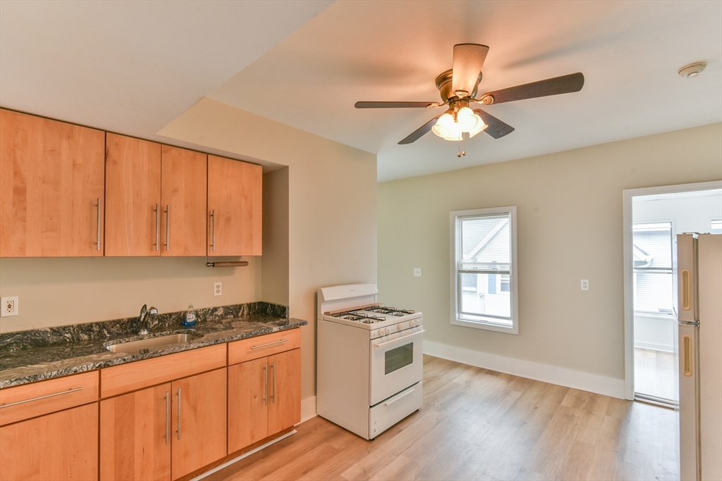 4 Agate Avenue Worcester, MA 01604 - Photo 5 of 39 a kitchen with granite countertop a stove a sink and white cabinets with wooden floor next to windows