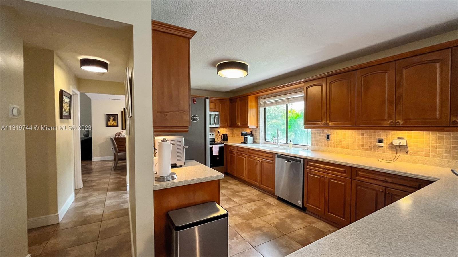 11990 Southwest 92nd Street Miami, FL 33186 - Photo 10 of 33 a large kitchen with stainless steel appliances a sink counter space and a window
