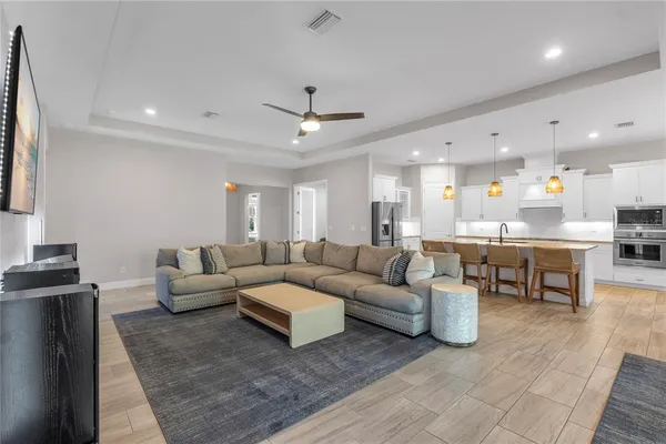 a living room with couches and kitchen view with wooden floor