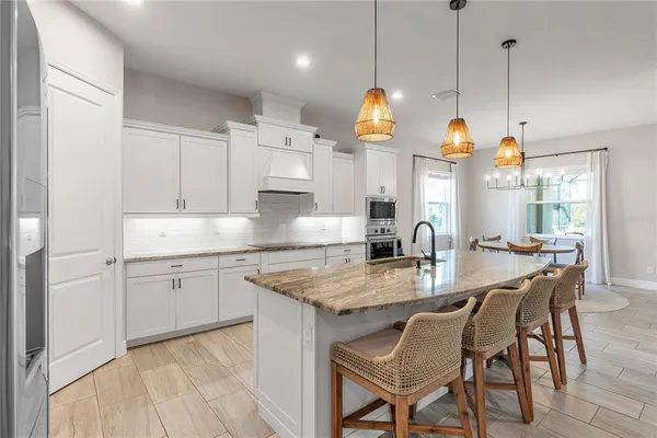 a kitchen with stainless steel appliances granite countertop a sink a stove a dining table and chairs