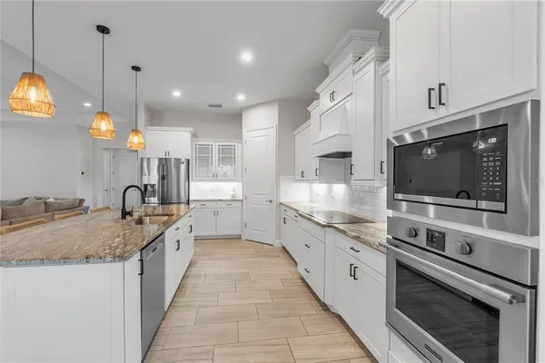 a large kitchen with stainless steel appliances granite countertop a stove a sink and a microwave