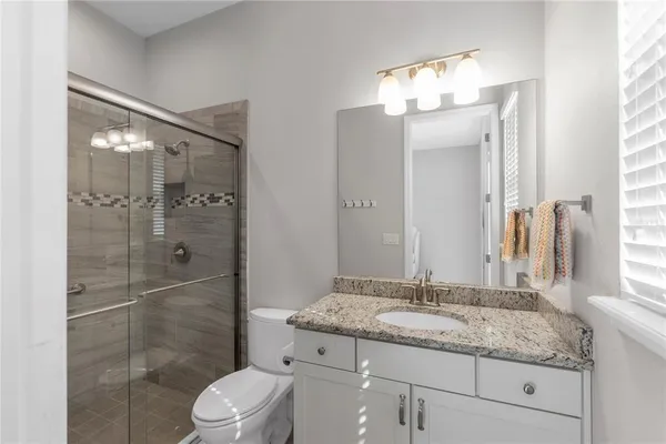 a bathroom with a granite countertop sink toilet a mirror and shower