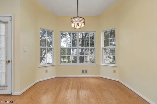 an empty room with wooden floor windows and cabinet