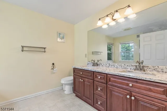a bathroom with a granite countertop sink a toilet and a mirror