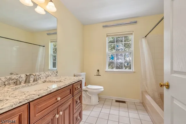 a bathroom with a granite countertop sink a toilet a mirror and shower