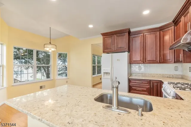 a kitchen with stainless steel appliances granite countertop a sink refrigerator and cabinets