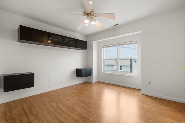 a view of empty room with wooden floor and fan