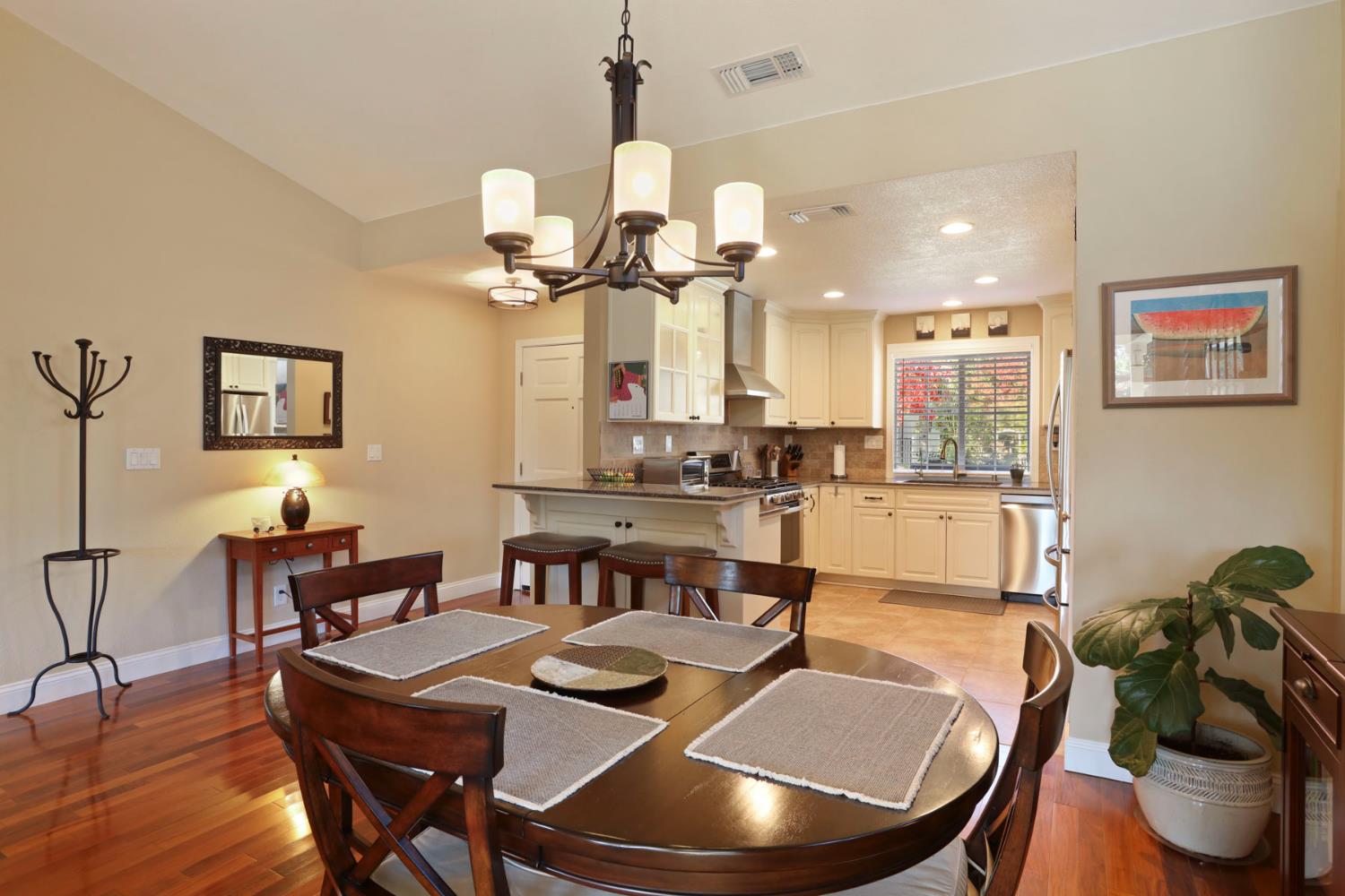 2832 Remington Way Tracy, CA 95377 - Photo 16 of 67 a dining room with wooden floor a chandelier a wooden table and chairs