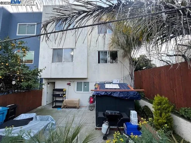 a backyard of a house with table and chairs potted plants and a large tree