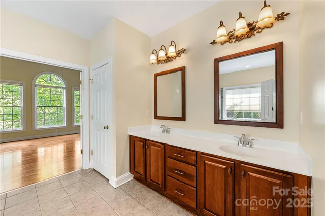 a bathroom with a double vanity sink a two mirror a window and a bathtub
