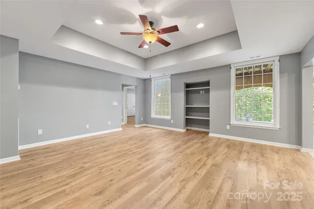 an empty room with a ceiling fan and window