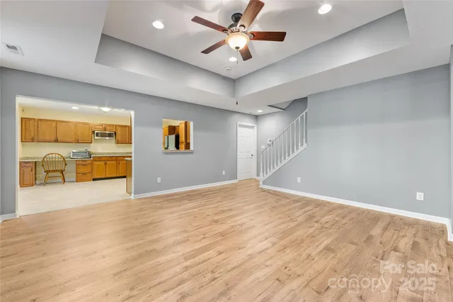 a view of an empty room with a window and a kitchen