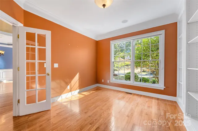 a view of an empty room with wooden floor and windows