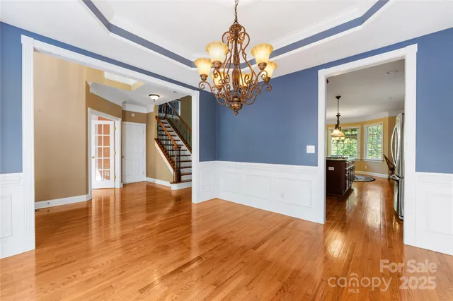 a view of a hallway with wooden floor and a chandelier