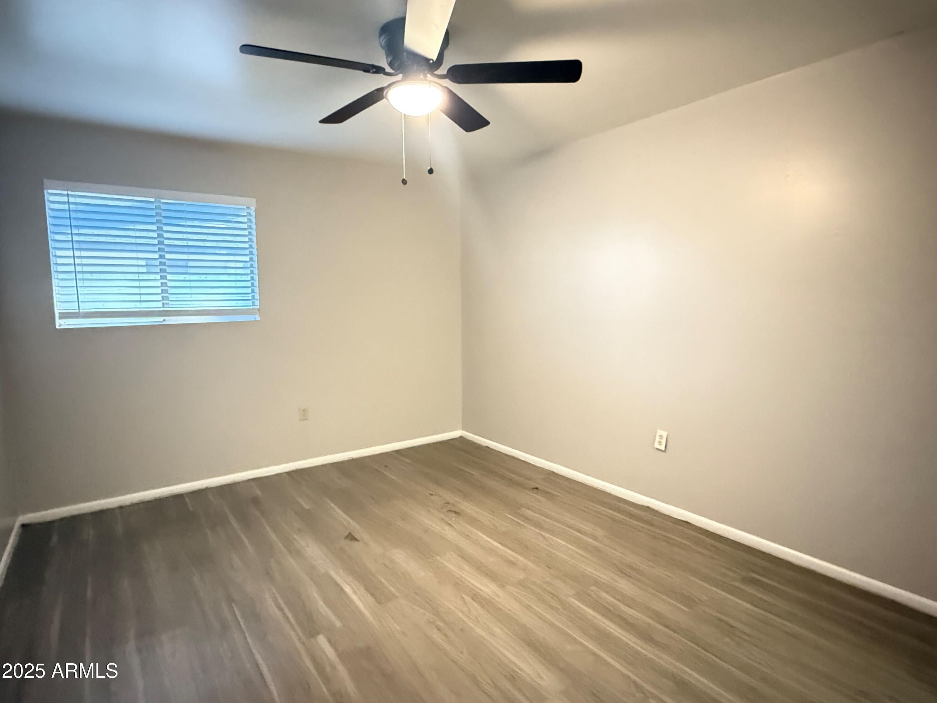 4719 North 15th Avenue, Unit 3 Phoenix, AZ 85015 - Photo 7 of 12 an empty room with wooden floor ceiling fan and windows