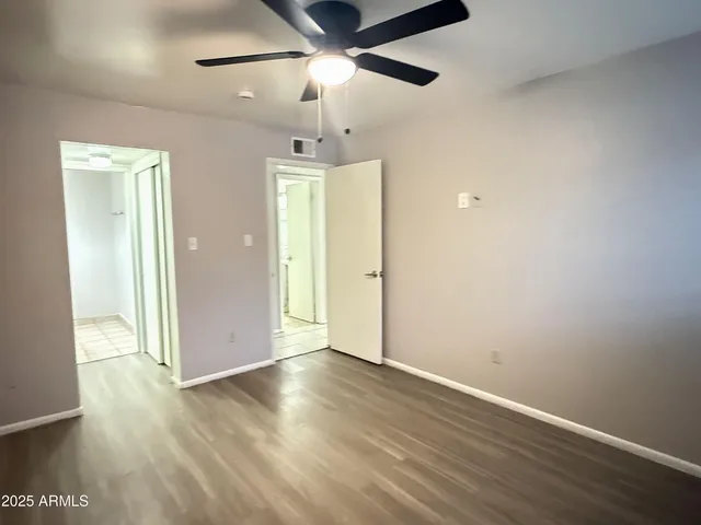 an empty room with wooden floor a ceiling fan and closet
