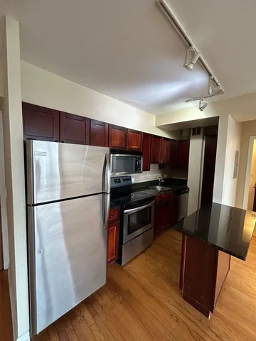 a kitchen with stainless steel appliances a refrigerator and wooden floor