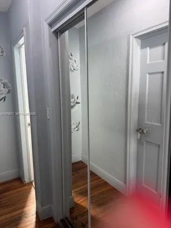a view of a hallway with wooden floor and a bathroom