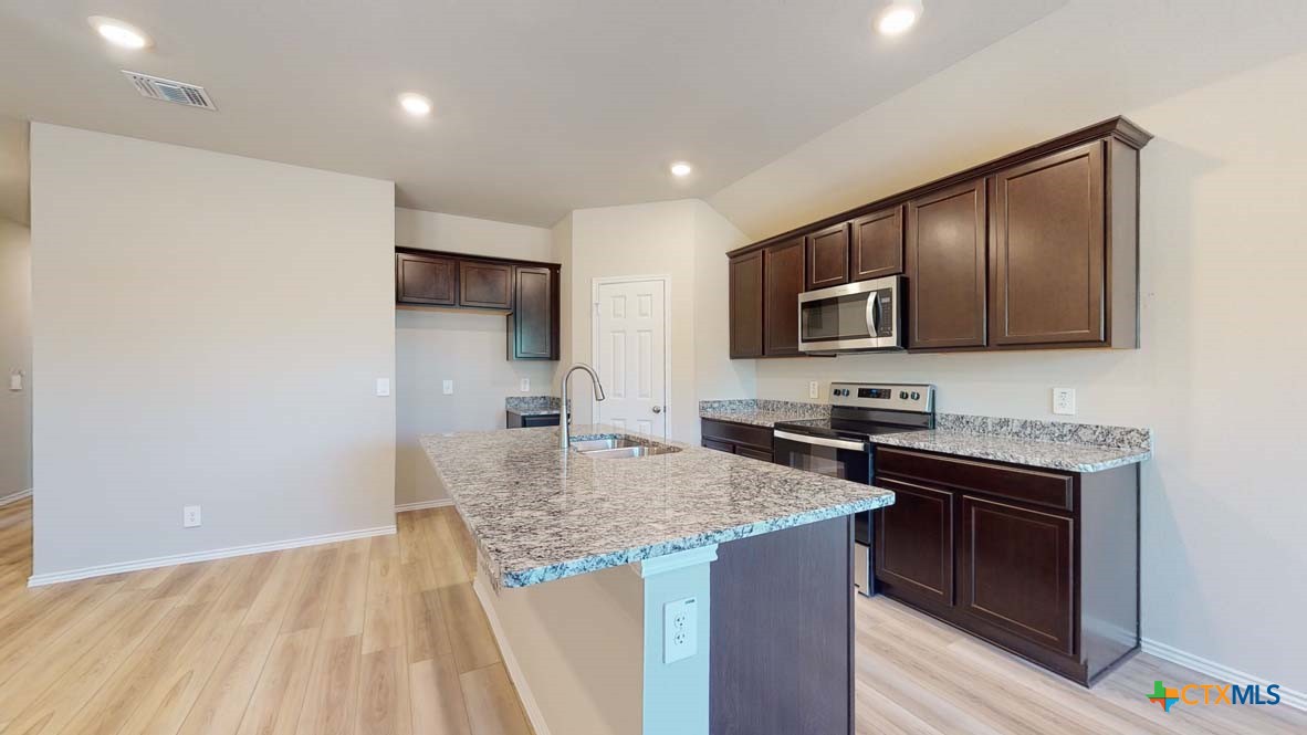 549 Hector Loop Georgetown, TX 78626 - Photo 7 of 22 a kitchen with stainless steel appliances granite countertop a sink stove microwave and refrigerator