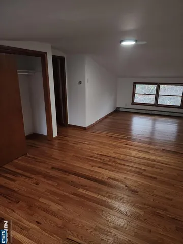 a view of empty room with window and wooden floor