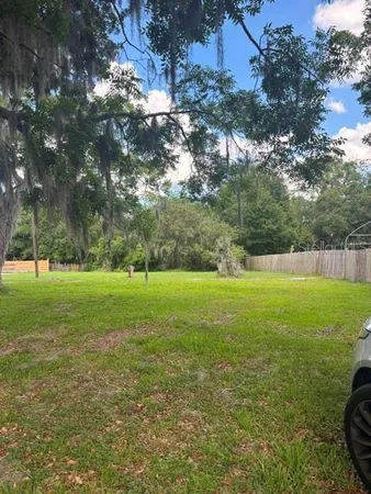 a view of yard with green space and trees