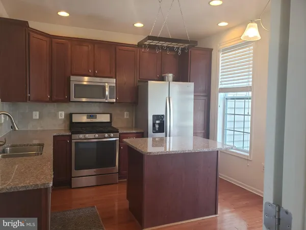 a kitchen with kitchen island granite countertop a stove cabinets and refrigerator