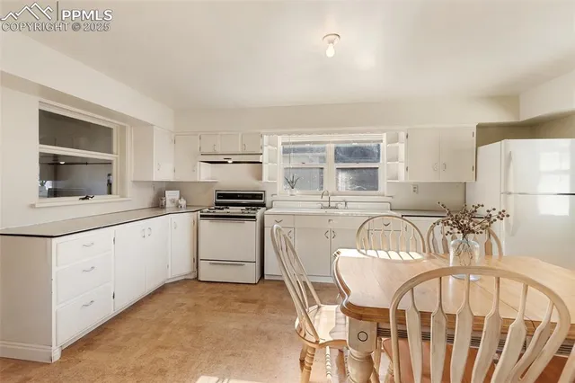 a kitchen with a table chairs a stove a microwave and cabinets