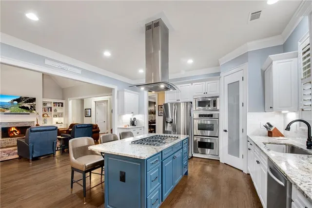 a large kitchen with kitchen island a large counter space a sink stainless steel appliances and cabinets