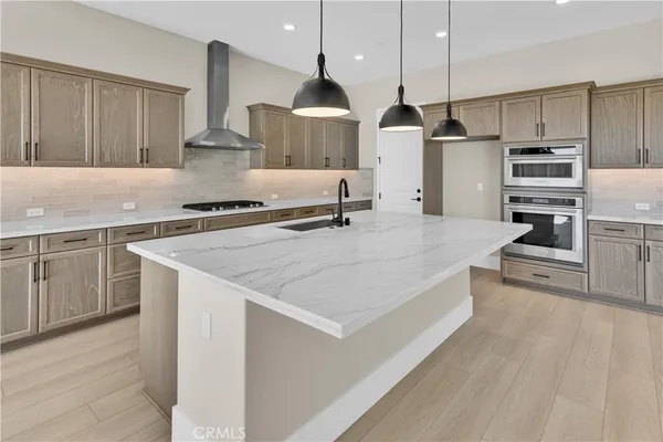 a large kitchen with stainless steel appliances a large counter top a stove a chimney a sink and a refrigerator