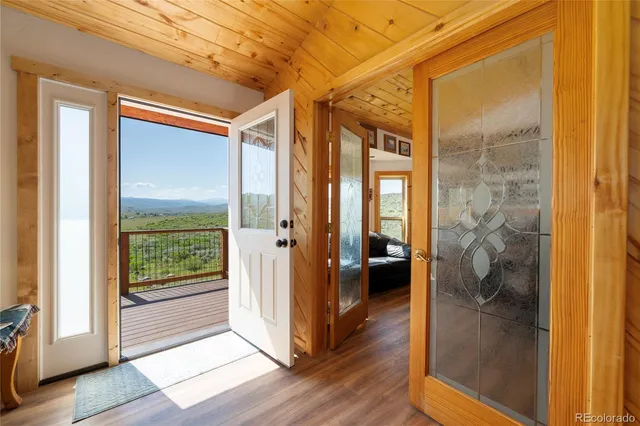 a view of a hallway with wooden floor and a bathroom
