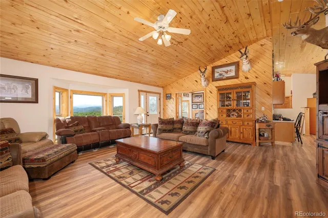 a living room with furniture a large window and wooden floor