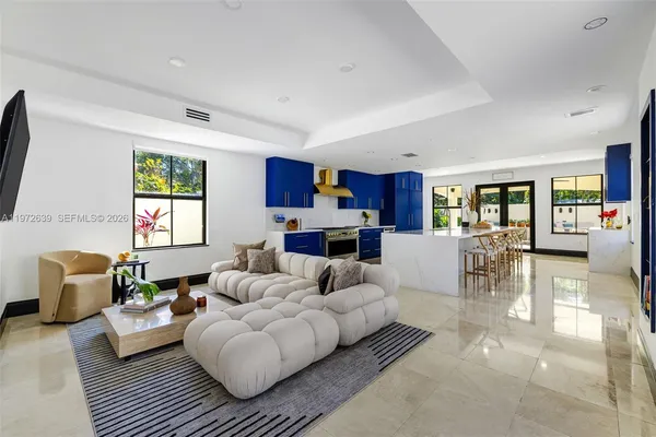a living room with furniture kitchen view and a large window