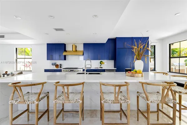 a kitchen with stainless steel appliances granite countertop a stove top oven a sink a dining table and chairs with wooden floor